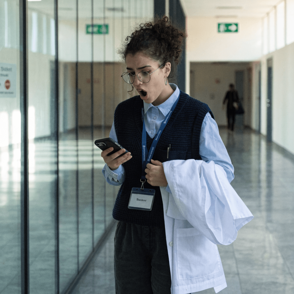 Medizinstudentin liest ihr Physikum-Ergebnis auf dem Handy